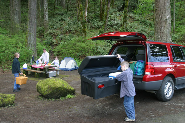 Boy getting something out of StowAway Standard Cargo Carrier on red SUV at a family campsite