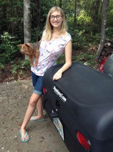 Sophia holding her dog and standing by StowAway Standard Cargo Carrier mounted on Nissan Versa