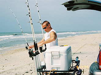 Fisherman at beach with fishing poles in StowAway Surf Fishing Rod Rack