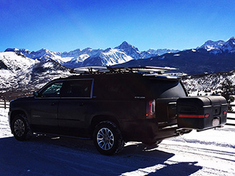 GMC Yukon XL with StowAway MAX Cargo Carrier driving on snowy road in mountains