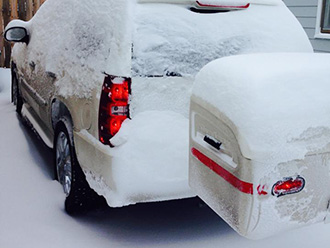 SUV with white StowAway MAX Cargo Carrier covered in snow