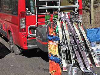 Winnebago Sprinter van with skis and snowboards leaning up against StowAway MAX Cargo Carrier