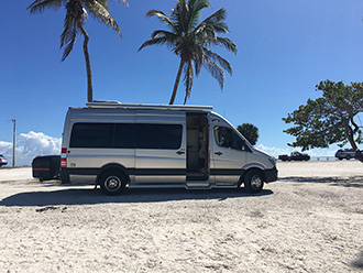 Pleasure-Way Plateau Sprinter van with StowAway MAX Cargo Carrier, parked under palm trees