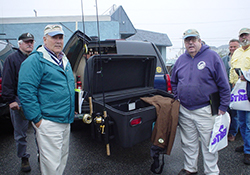 StowAway Standard Cargo Carrier with lid open holding fishing rods, two men standing nearby