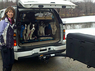Three dogs in crates in back of GMC Yukon with StowAway MAX Cargo Carrier swung out